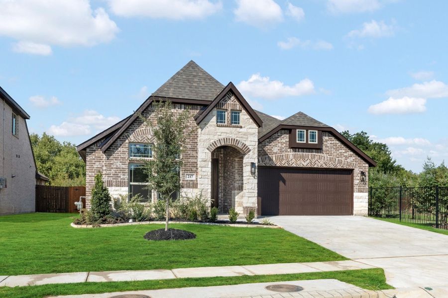 Single-story home with brick and stone exterior, arched entry, two-car garage, and manicured front lawn