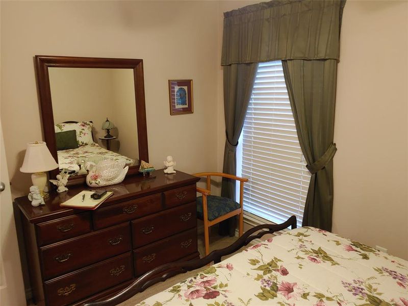 Room featuring light-colored walls, a window with horizontal blinds, and green fabric drapes with a matching valance