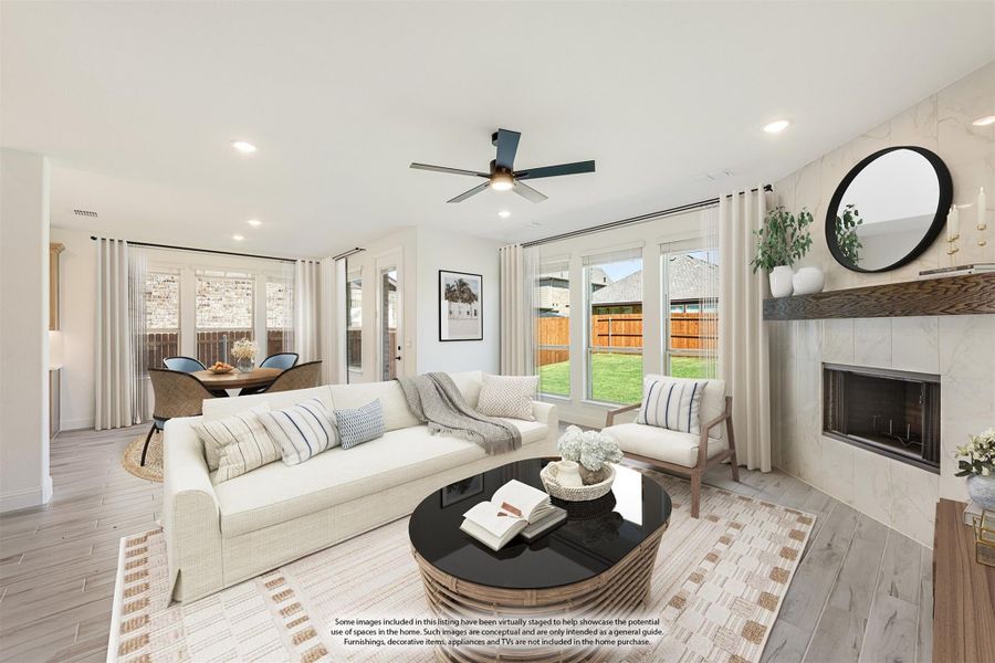 Living room with white sofa, tile fireplace, ceiling fan, and backyard views through large windows Living room with white sofa, tile fireplace, ceiling fan, and backyard views through large windows