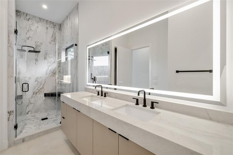 Dual vanity with integrated sinks and matte black fixtures, set beneath an illuminated mirror Dual vanity with integrated sinks and matte black fixtures, set beneath an illuminated mirror