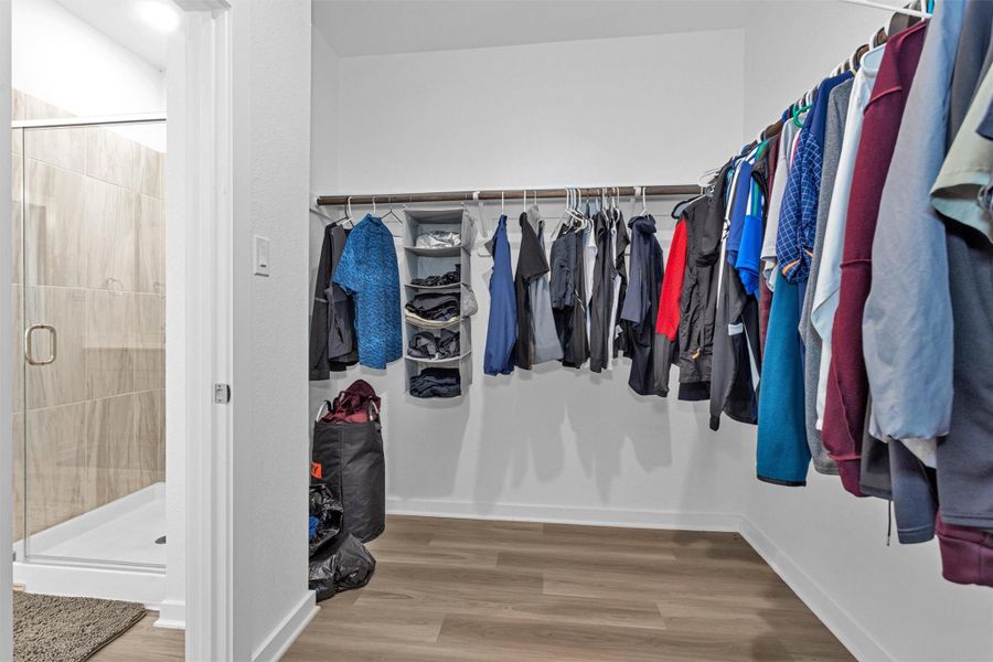 This spacious walk-in closet offers generous hanging space, open shelving, and a well-organized layout, providing ample room for clothing, shoes, and accessories.