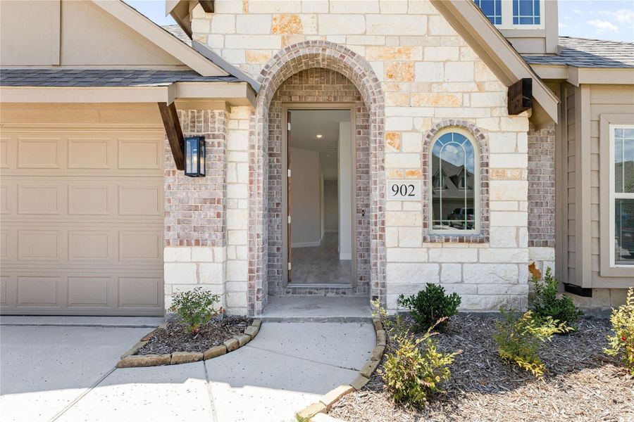 Home entrance with arched brick doorway, stone exterior, address number 902, and attached garage Home entrance with arched brick doorway, stone exterior, address number 902, and attached garage