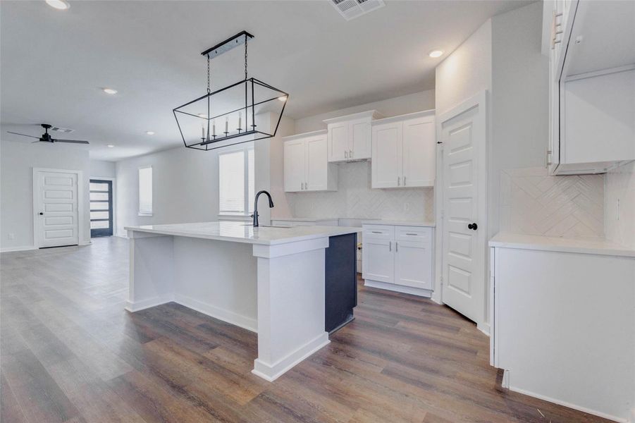 Step inside to an open-concept layout where the kitchen seamlessly flows into the living and dining areas. Wide-plank flooring, soft neutral tones, and recessed lighting provide a clean backdrop for your personal style. An oversized island anchors the space with modern flair and function.