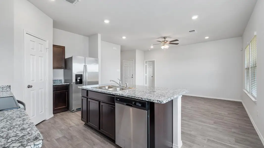 Kitchen featuring stainless steel appliances, light wood-style floors, a kitchen island with sink, ceiling fan, and dark wood finish cabinets