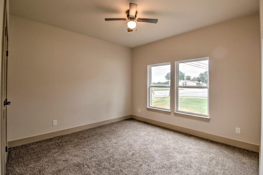 Carpeted empty room featuring baseboards and ceiling fan