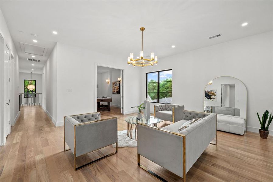 Bright interior space featuring light hardwood flooring, recessed lighting, and a modern chandelier