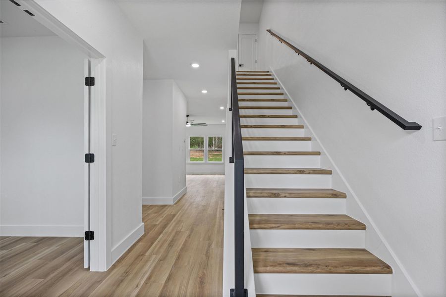 Modern staircase featuring wood-finish treads, white risers, and contemporary black metal railings Modern staircase featuring wood-finish treads, white risers, and contemporary black metal railings