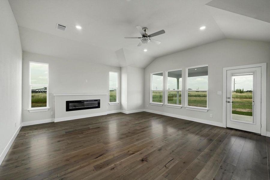 Unfurnished living room featuring lofted ceiling, ceiling fan, dark wood-style flooring, a glass covered fireplace, and recessed lighting