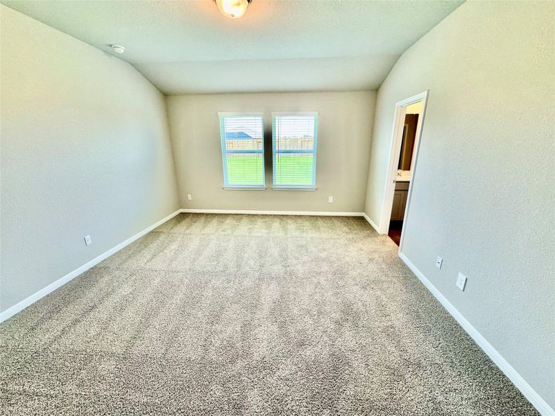Spare room with carpet flooring, vaulted ceiling, and a textured wall