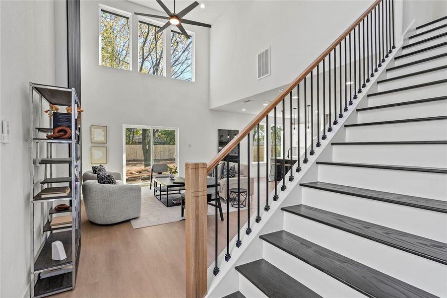 Staircase featuring hardwood / wood-style floors, ceiling fan, and a high ceiling