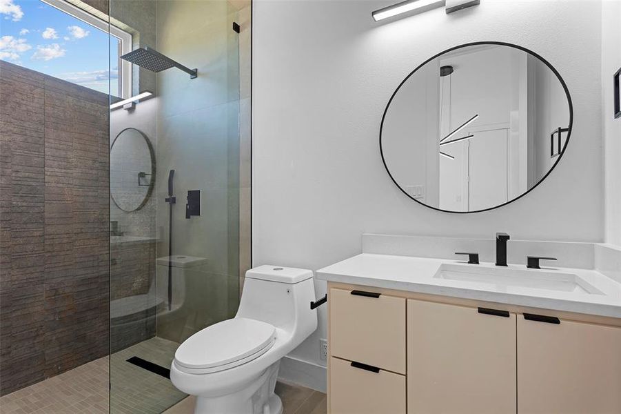 Bathroom featuring a shower with door, toilet, and vanity