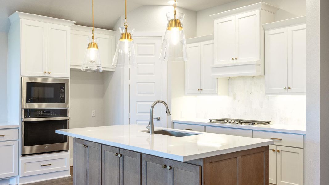 Kitchen with white cabinetry, appliances with stainless steel finishes, and pendant lighting