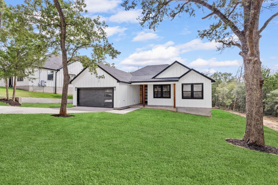Modern inspired farmhouse with a front lawn, a shingled roof, driveway, board and batten siding, and a garage