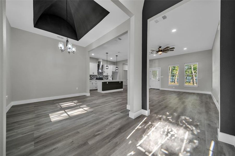 Unfurnished living room featuring ceiling fan with notable chandelier and hardwood / wood-style flooring