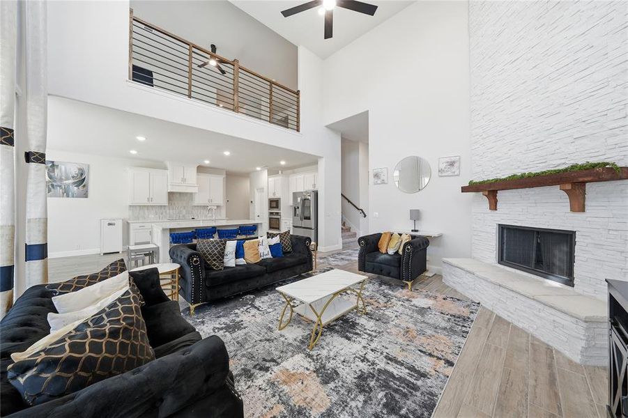 Living room featuring light wood-type flooring, a fireplace, a high ceiling, and stairway