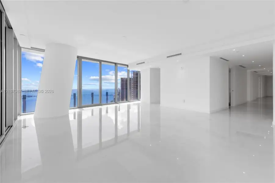 Open-concept interior featuring floor-to-ceiling glass windows, water and skyline scenery, polished tile flooring, and recessed ceiling lighting