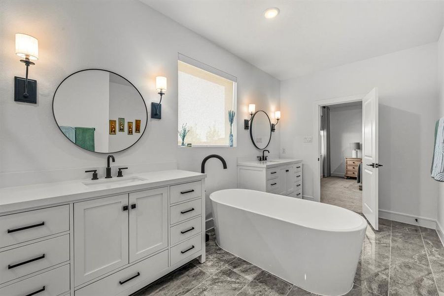 Primary bathroom with a freestanding bath, two vanities, and recessed lighting