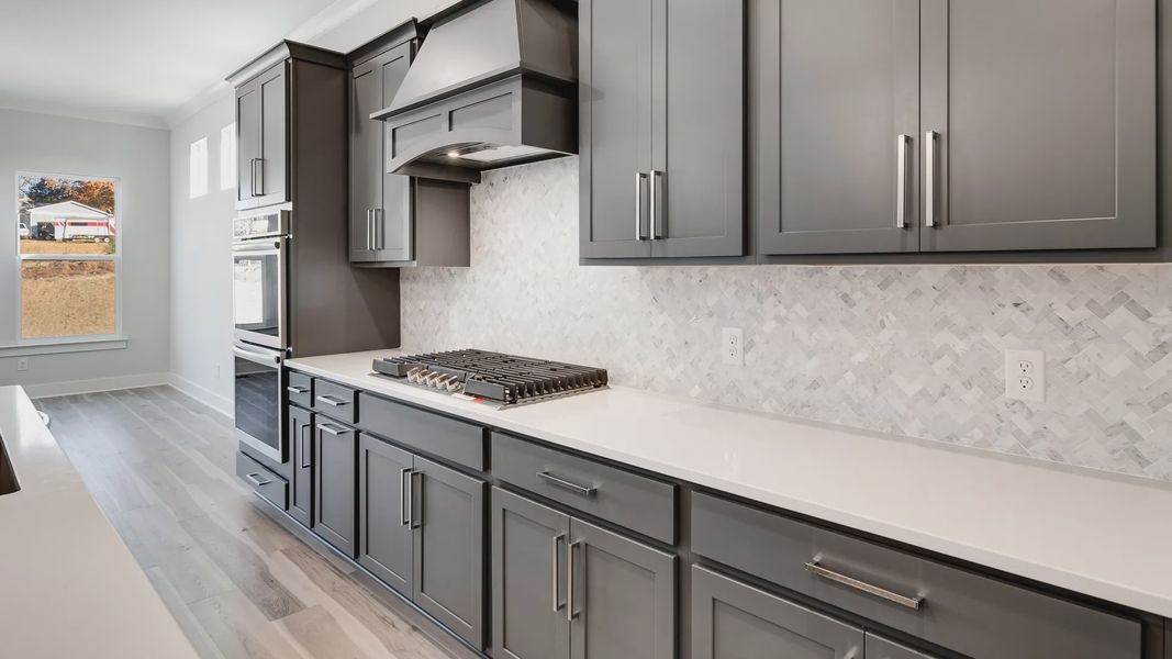 Modern kitchen with island, gray cabinets, and tile backsplash. Showing Optional Gas cooktop