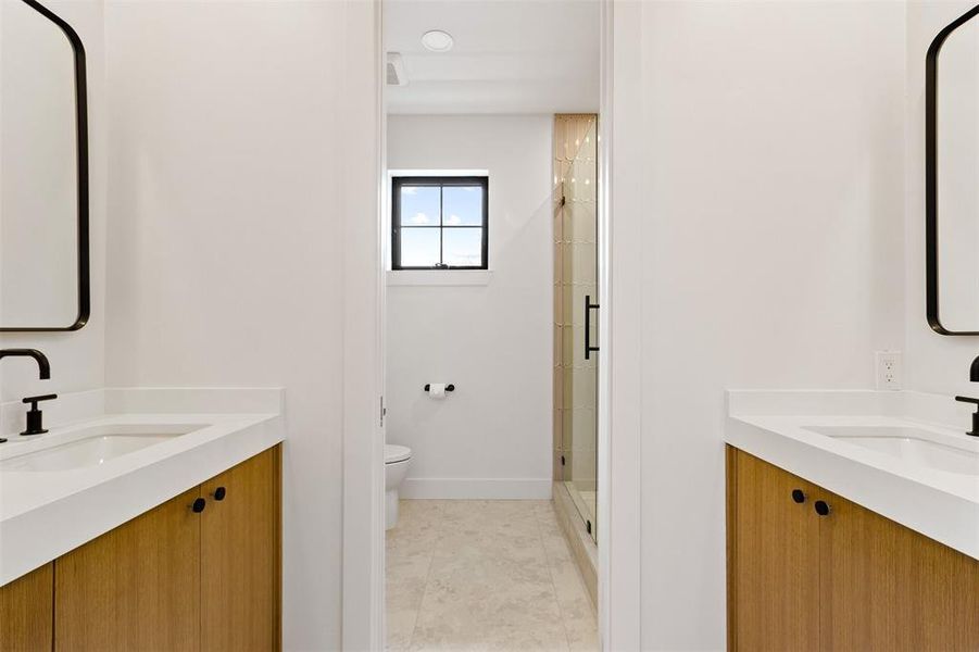 Bathroom with a shower stall, two vanities, and tile patterned flooring