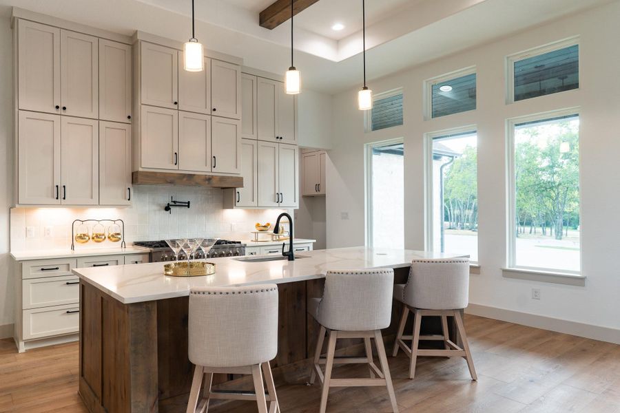 Kitchen with decorative backsplash, light wood-style flooring, light stone counters, an island with sink, and recessed lighting Kitchen with decorative backsplash, light wood-style flooring, light stone counters, an island with sink, and recessed lighting