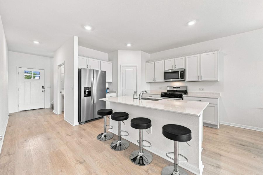 Gleaming stone countertops and wood flooring define this open kitchen design.