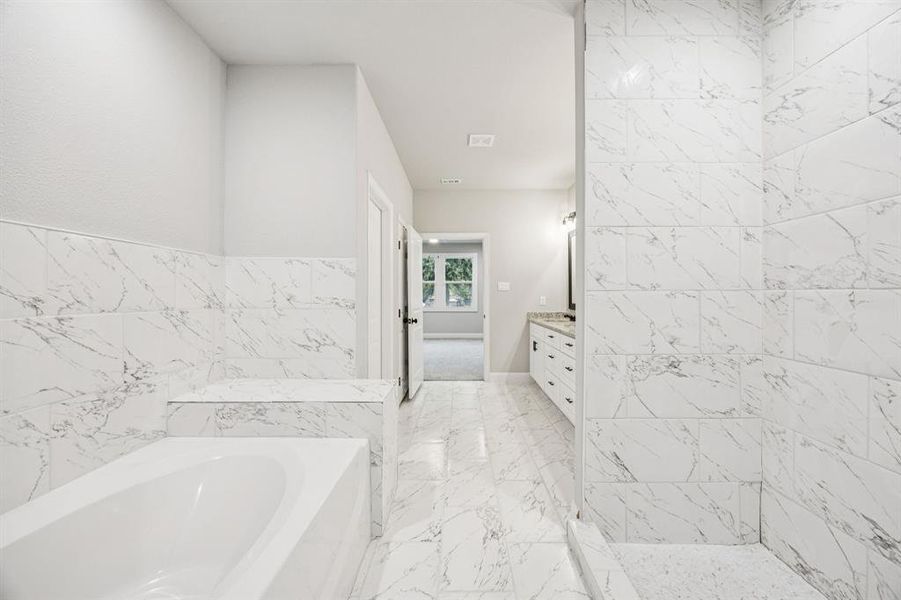 (Bedroom #1) Master bathroom with vanity, a bath, tile walls, granite countertops and light marble finish floors