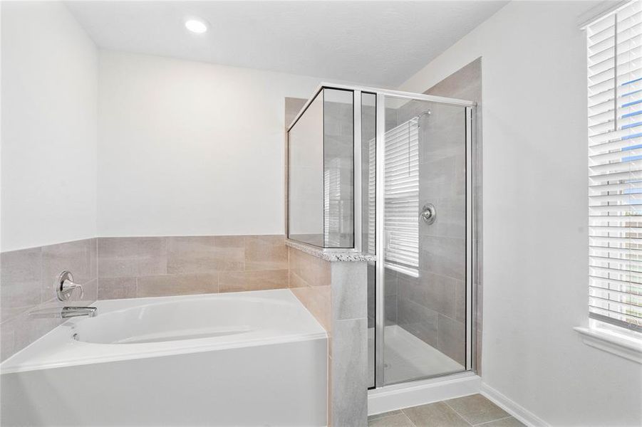 This primary bathroom is definitely move-in ready! Featuring an oversized framed walk-in shower with tile surround, separate garden tub for soaking after a long day with custom tile detailing, stained cabinets with light countertops, high ceilings, neutral paint, sleek and modern finishes.