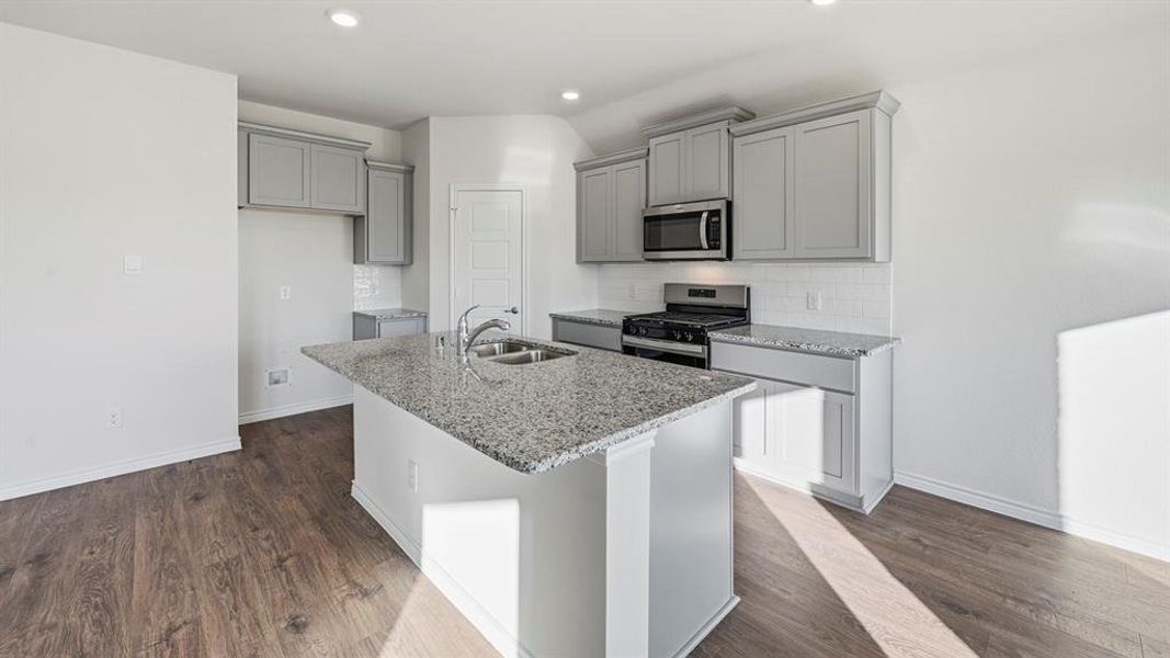 The property features a contemporary kitchen with light grey cabinetry, granite countertops, and stainless steel appliances, including a microwave and gas range