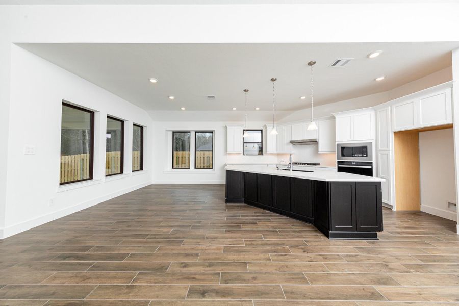 The dining area is filled with natural light and features high ceilings, recessed lighting, and expansive windows.