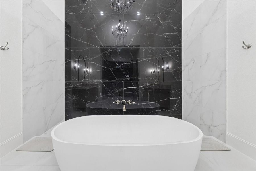 Anchored by a striking freestanding tub, this elegant retreat evokes the atmosphere of a private luxury spa. The dramatic stone feature wall creates a stunning focal point while enhancing the room's timeless sophistication.