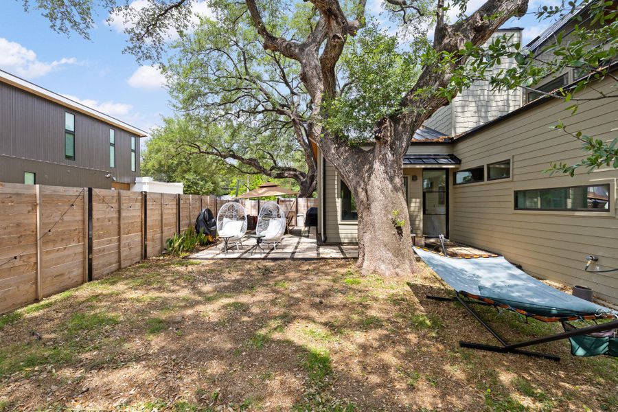 A spacious backyard retreat features mature trees, a private fence, and a comfortable patio area. A spacious backyard retreat features mature trees, a private fence, and a comfortable patio area.