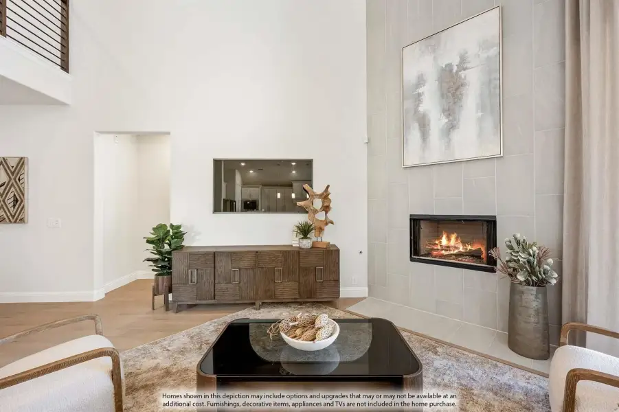 Living room with two-story ceiling, tile fireplace, hardwood floors, and modern furniture