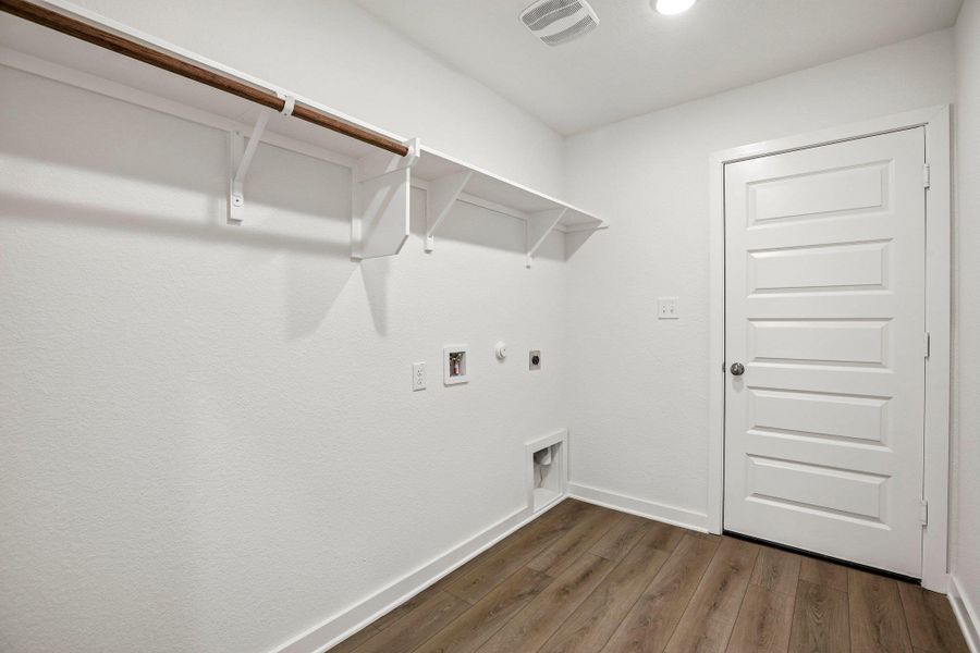 Functional layout highlights this utility space featuring durable wood floors and overhead storage shelves.