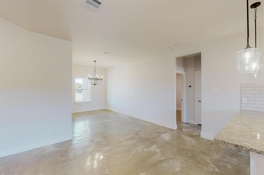 Unfurnished room featuring concrete flooring and a chandelier