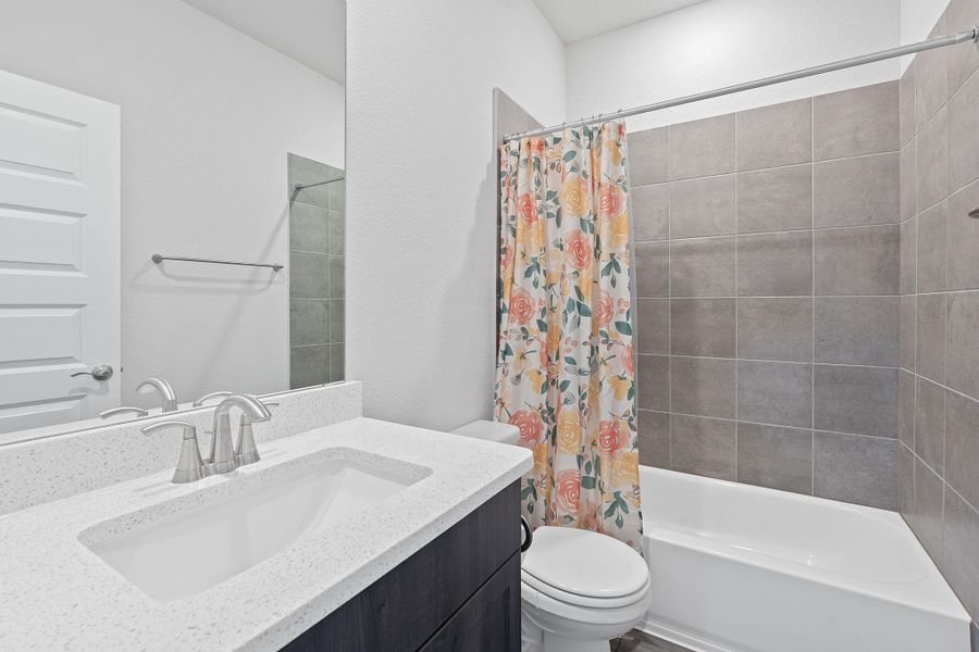 Full bathroom featuring toilet, vanity, and shower / bath combination with curtain Full bathroom featuring toilet, vanity, and shower / bath combination with curtain