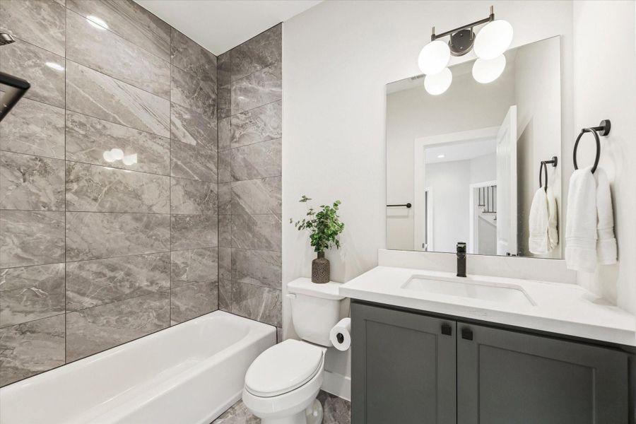 Ensuite bath with a shower/tub combo and quartz counters.