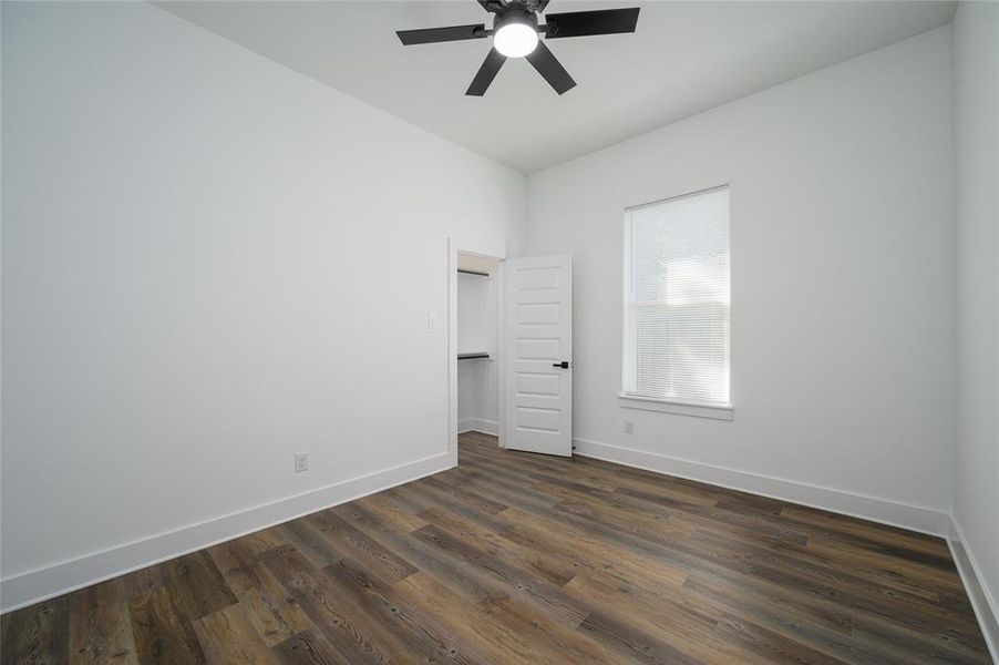 Unfurnished bedroom featuring dark hardwood / wood-style flooring and ceiling fan