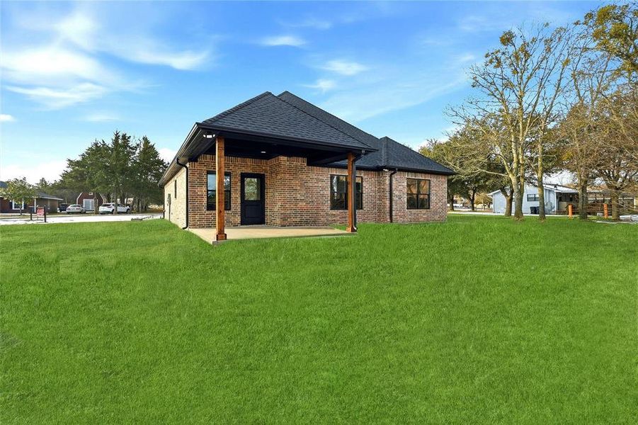 Rear view of property with a patio area, brick siding, a lawn, and a shingled roof Rear view of property with a patio area, brick siding, a lawn, and a shingled roof