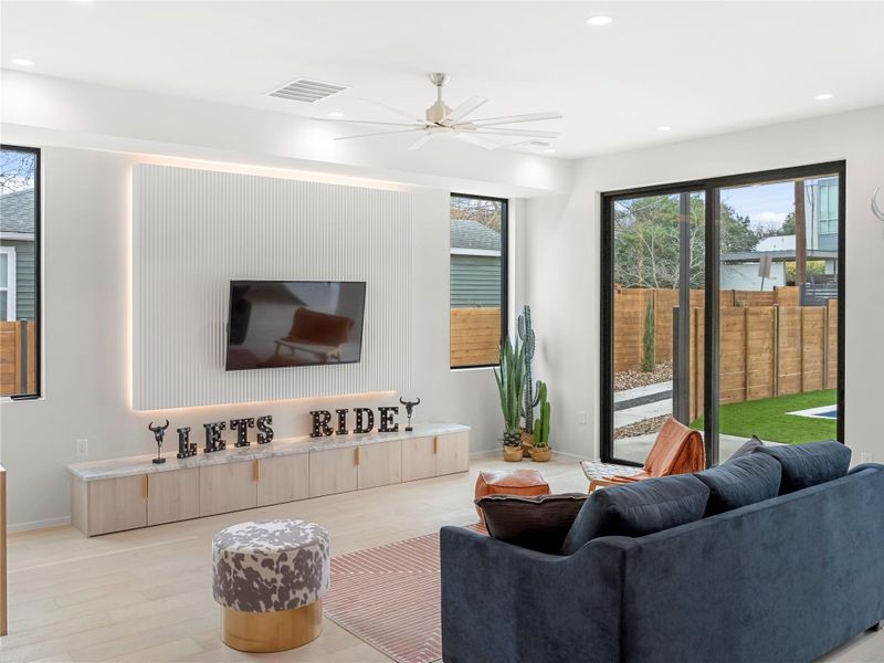Living area with light wood-type flooring, a ceiling fan, and recessed lighting