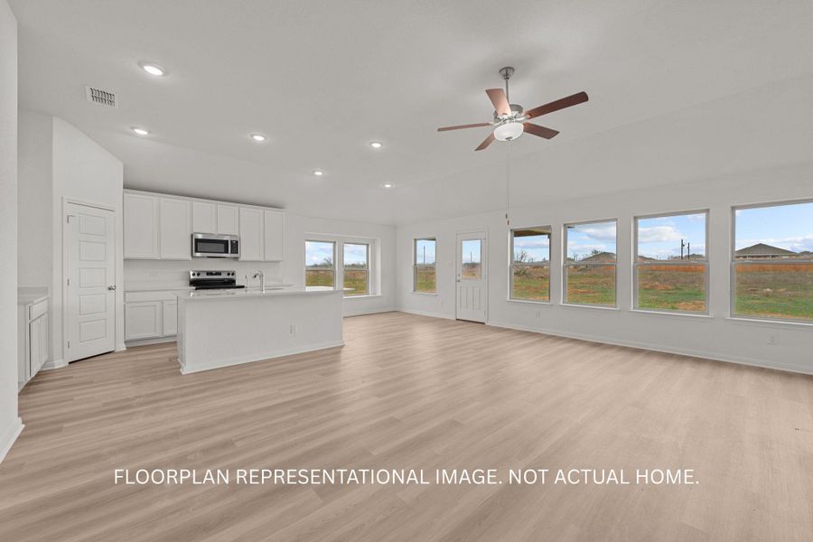 An open-concept living area flows seamlessly into the kitchen, illuminated by abundant windows and recessed lighting.