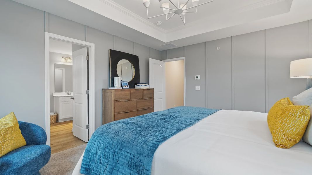 Stylish primary suite in new construction townhome featuring tray ceiling and bright modern palette in Auburn Ridge.