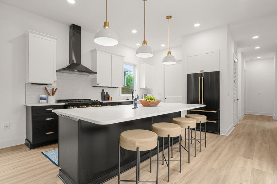 Kitchen featuring a kitchen breakfast bar, hanging light fixtures, dark cabinetry, high quality fridge, and a center island with sink Kitchen featuring a kitchen breakfast bar, hanging light fixtures, dark cabinetry, high quality fridge, and a center island with sink