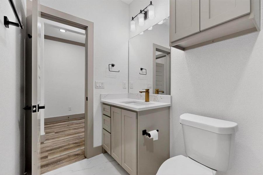 Half bathroom with vanity and light marble finish floors