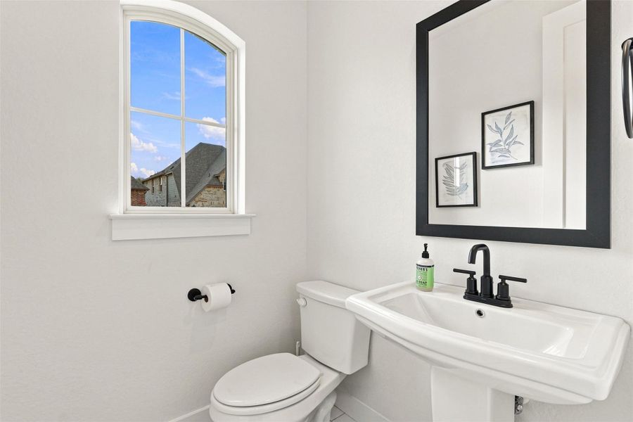 An arched window invites natural light into this classic powder room.