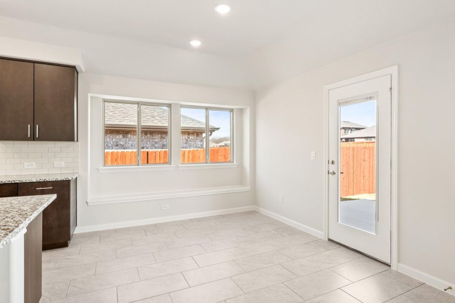 Bright dining nook with tile floors, large window, and glass back door next to dark wood kitchen cabinets Bright dining nook with tile floors, large window, and glass back door next to dark wood kitchen cabinets