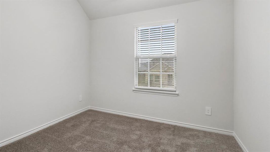 Spare room featuring dark carpet and lofted ceiling
