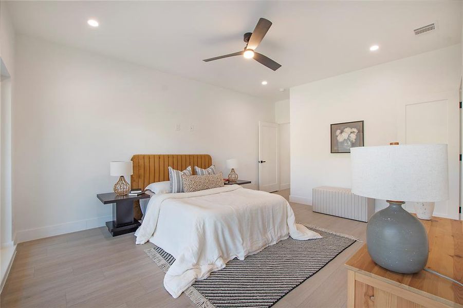 Bedroom featuring radiator heating unit, light hardwood / wood-style floors, and ceiling fan