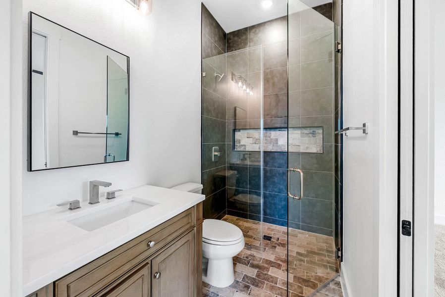 A well-appointed bathroom features a glass-enclosed shower and a modern vanity with ample counter space.