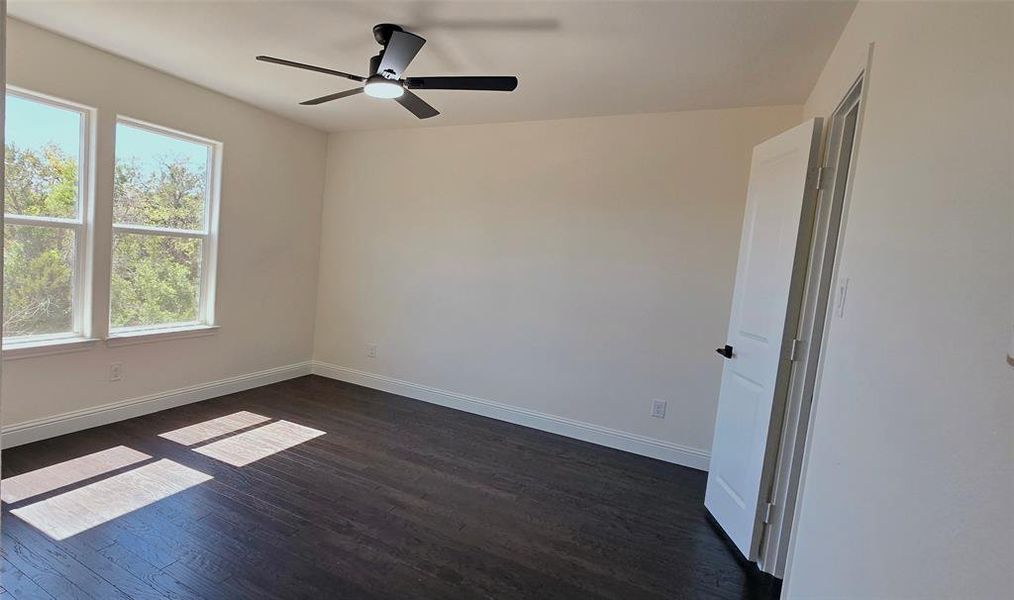 Spare room featuring dark wood-style floors and ceiling fan Spare room featuring dark wood-style floors and ceiling fan