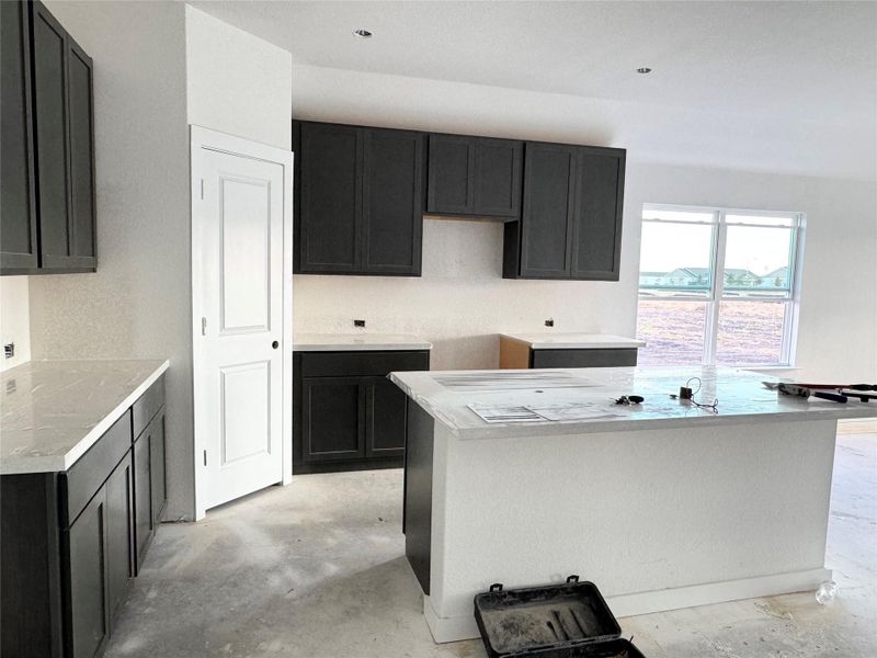Kitchen featuring unfinished concrete floors, a kitchen island, and dark cabinetry